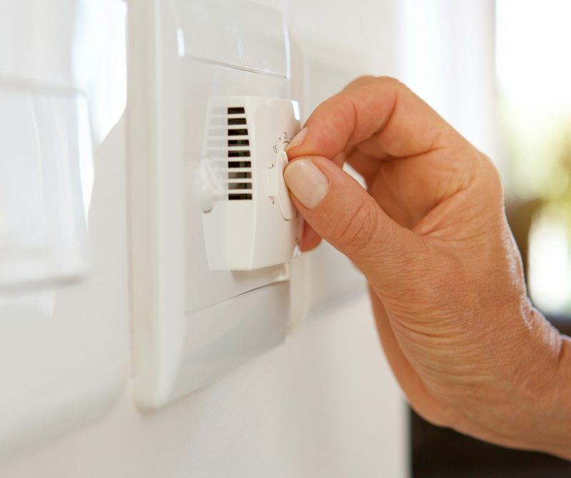 female hand adjusting temperature with dial on air conditioning