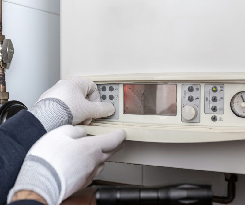 Technician servicing heating boiler in a house